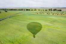 Shadow Of Hot Air Balloon On Field Against Sky