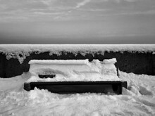 Snow Covered Bench By Retaining Wall Against Sky During Winter