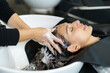 hairdresser is applying shampoo and massaging hair of a customer. Woman having her hair washed in a hairdressing salon..