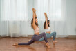 © svetograph - Two attractive athletic girls train asana yoga pose on mats on a light background. A group of young women stretch out in the gym. Healthy lifestyle concept