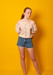 Cute teen girl wearing a fashionable shirt and denim shorts. Skinny teenage girl.