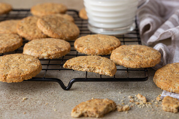 Wall Mural - Healthy oatmeal cookies with cereals, seeds and nuts with a cup of milk on concrete background. Diet vegan cookies.