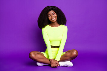 Poster - Full size photo of young beautiful charming smiling afro sportive woman sit floor relaxing isolated on purple color background