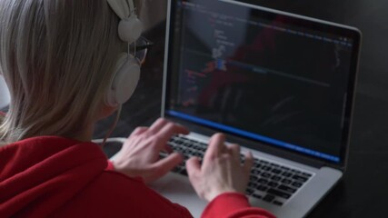 view as woman in glasses working with code on laptop computer.