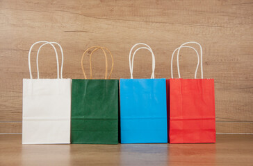 Wall Mural - Colorful paper shopping bags on the floor against a wooden wall background