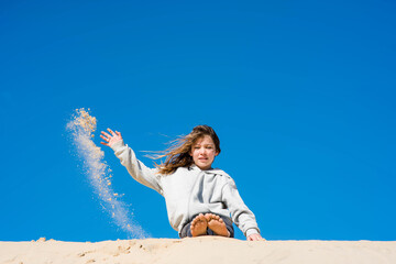 Wall Mural - cute little girl having fun with sand dunes