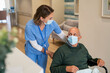 © Rido - Nurse helping man in wheelchair at care facility centre