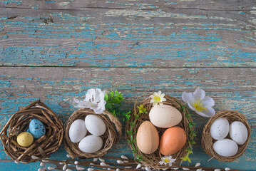 Wall Mural - Happy Easter holiday background. Birdnests with eggs, flowers on old blue paint wooden background. Space for text, top view