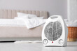 © New Africa - Modern electric fan heater on floor in light bedroom. Space for text