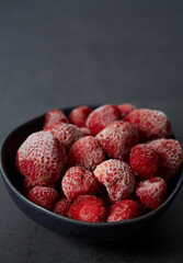 Wall Mural - Frozen strawberries on a black background. Berries are being preserved for winter.