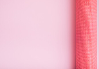 Monochrome fitness theme with pink yoga exercise mat on light background. Flat lay with copy space.