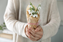 Woman Holding Paper Bag With Beautiful Snowdrops And Traditional Cord Martisor Indoors, Closeup. Symbol Of First Spring Day