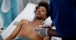 Doctors placing ecg electrodes on young unconscious afro-american patient