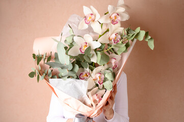 Woman holding a beautiful bouquet with flowers on green background. Front view. Valentine's, women's, mother's day, love concept. 8th of march.