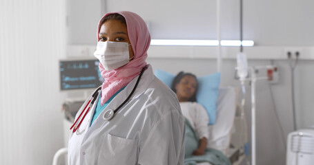 Wall Mural - Portrait of arabian woman doctor in protective mask looking at camera working at hospital