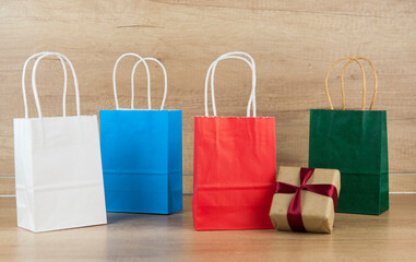 Wall Mural - Colorful paper shopping bags on the floor against a wooden wall background