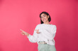 © Анастасия Каргаполов - Woman in casual white sweater on pink red background smile and point left isolated copy space