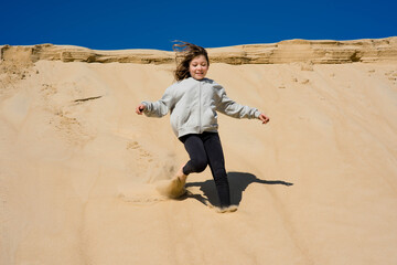 Wall Mural - cute little girl running in the sand