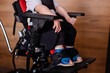 © Antipina - Toddler sits in a special wheelchair at home. Child with cerebral palsy. Disability. Orthopedic shoes. Rehabilitation inclusion. Lifestyle