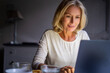© PhotoAlto - Smiling mature woman using laptop at home