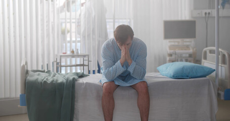 Portrait of man patient sitting on bed in hospital feeling stressed