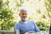 Portrait Of Smiling Mature Man Sitting On Chair