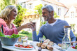 © PhotoAlto - Smiling mature couple toasting wine glasses while sitting at table