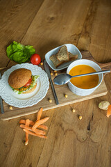 Sticker - Delicious veggie burger and a bowl of pumpkin soup on a wooden board in the kitchen