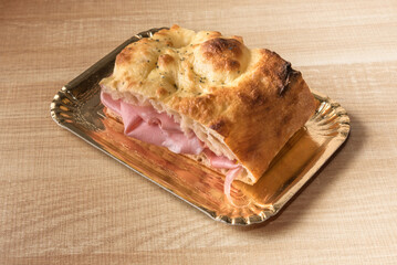 Wall Mural - Focaccia bread sandwich filled with bologna mortadella in takeaway tray isolated on wooden background