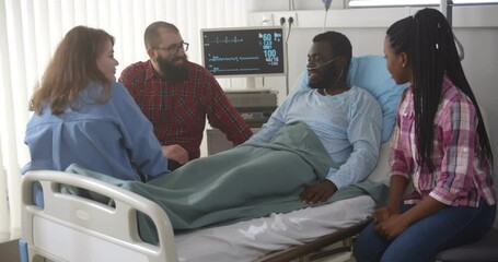 Wall Mural - Diverse friends visiting sick african man in hospital ward