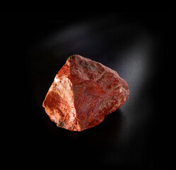 Raw red feldspar mineral nugget from Tian Shan mountains isolated on black background. For geology mineralogy magazines websites article, Natural Science museum wall charts and posters etc