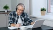 A man wearing headphones participates in online negotiations on a laptop.