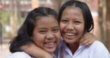 Slow Motion Scene Of Two Young Native Asian Female Student Girls In White Uniform Who Had Pimple On Their Foreheads Are Laughing Happily And Joyful Together On The Natural Bokeh Background.