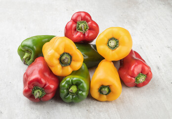 Green, red and yellow bell peppers over rustic background