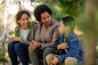 © bernardbodo - Black single mother sitting with their children in park