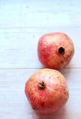 two handsome pomegranates, red fruit, pomegranates on a light wooden background, pomegranates