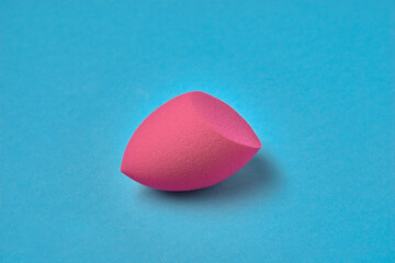 pink makeup blender sponge, close-up. Applying beauty facial cosmetics foundation, a tool for perfect makeup. bb-cream or concealer on a blue aqua background