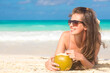 © el.rudakova - young woman smiling lying in straw hat in sunglasses with coconut on beach
