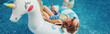 Girl in sunglasses with drink lying on inflatable ring unicorn. Kid child enjoying having fun relaxing in swimming pool on floatie. Summer outdoor water activity for kids. Web banner header.