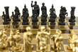Black against gold army soldier chess pieces on a chessboard on a white background