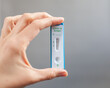 © Anastasia - hand holding positive rapid antigen test Covid-19 on a grey background