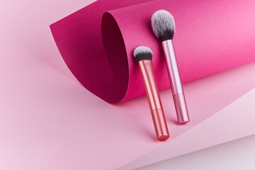 makeup brushes on pink and burgundy paper background. cosmetic professional make up brushes