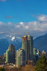 Wall Mural - Construction of new high-rise buildings in residential district in Burnaby City, construction site in the center of the city at the backdrop of a snow covered mountain ridge