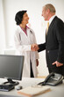 © Tetra Images/Tetra Images - Female doctor shaking hands with hospital executive