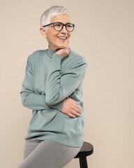 Senior female studio portrait. Short grey hair senior model. Fashion photography in studio. Old female wearing glasses. Confident senior female portrait.