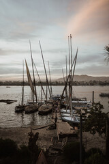 Poster - Vertical shot of a port with sailboats on the background of buildings and mountains at sunset