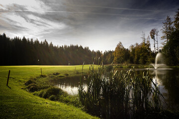 Wall Mural - Scenic view at a golf course near a lake under a gloomy sky background