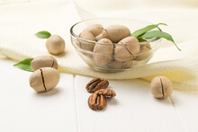 Pecans In A Glass Bowl On A Piece Of Cloth On A White Wooden Table.
