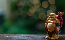 Happy Laughing Buddha Standing On Wooden Table Wth Nature Blurred Background.
