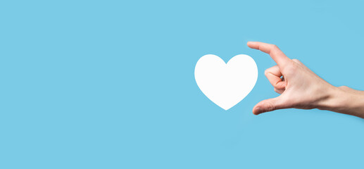 Wall Mural - Male hand holding heart , like icon on blue background. Kindness, charity, pure love and compassion concept.Banner with copy space